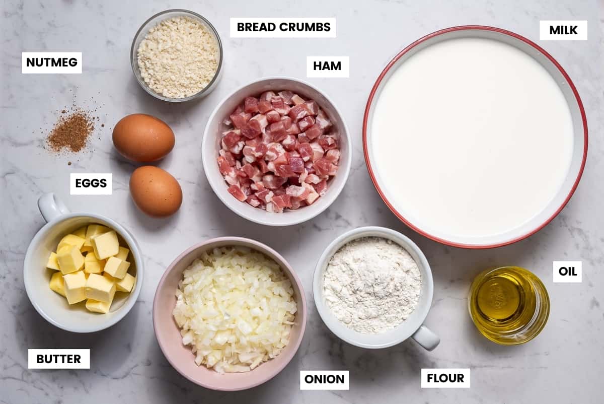 Ingredients to make Spanish ham croquettes laid out on white marble counter.