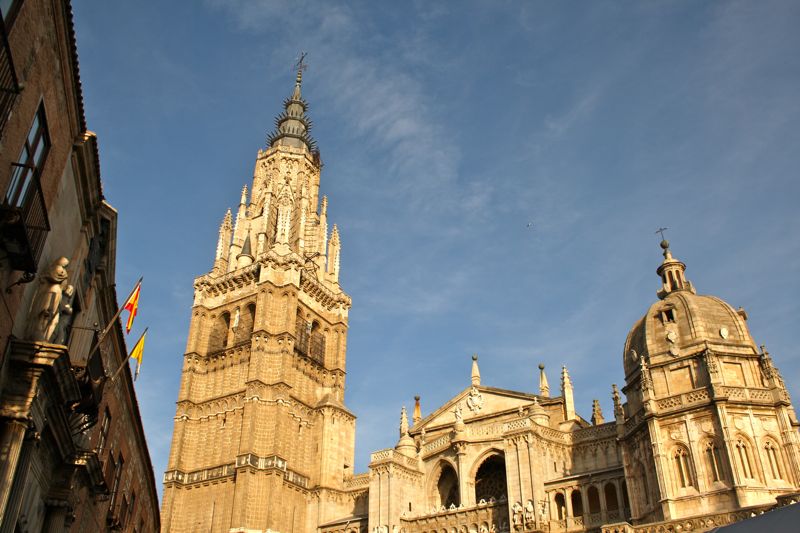 The ornate Toledo Cathedral and its tall tower, with blue sky in the background.