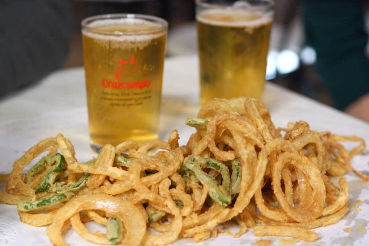 Fried rings of onions and pepper in front of two small glasses of draft beer.