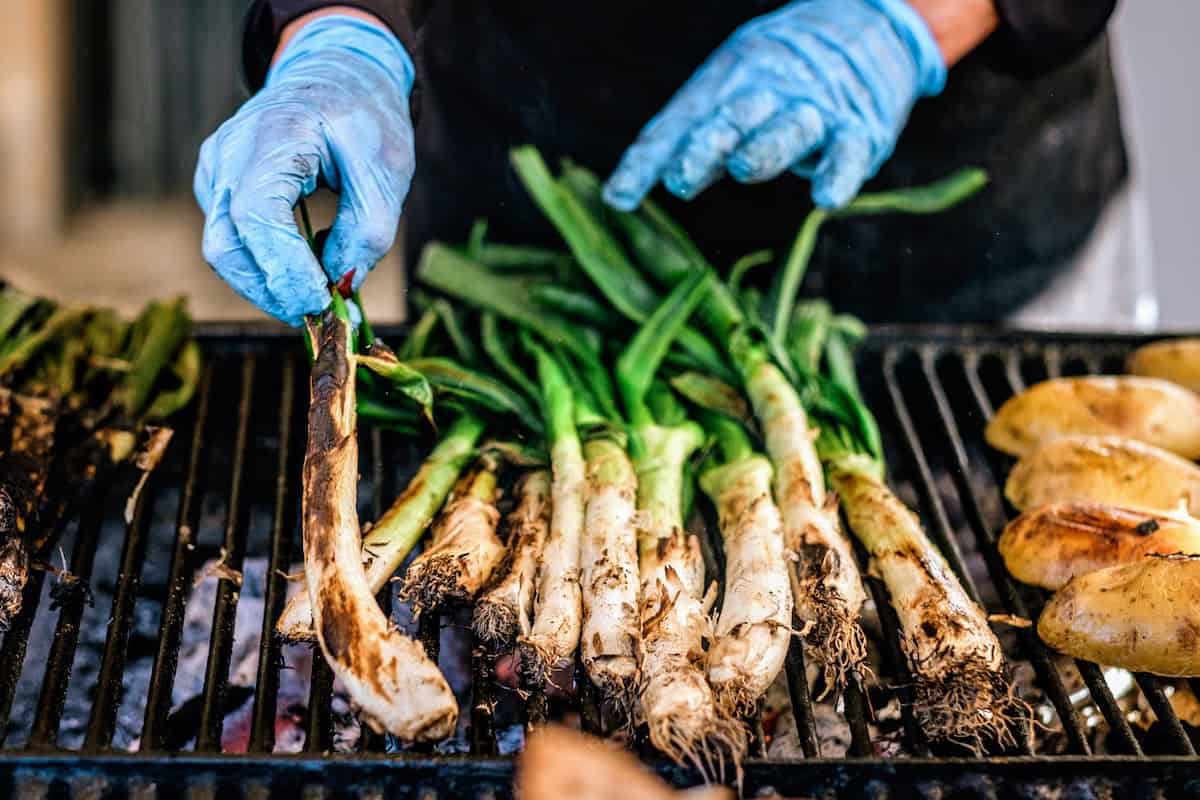 Spring onions with green stalks on a grill.