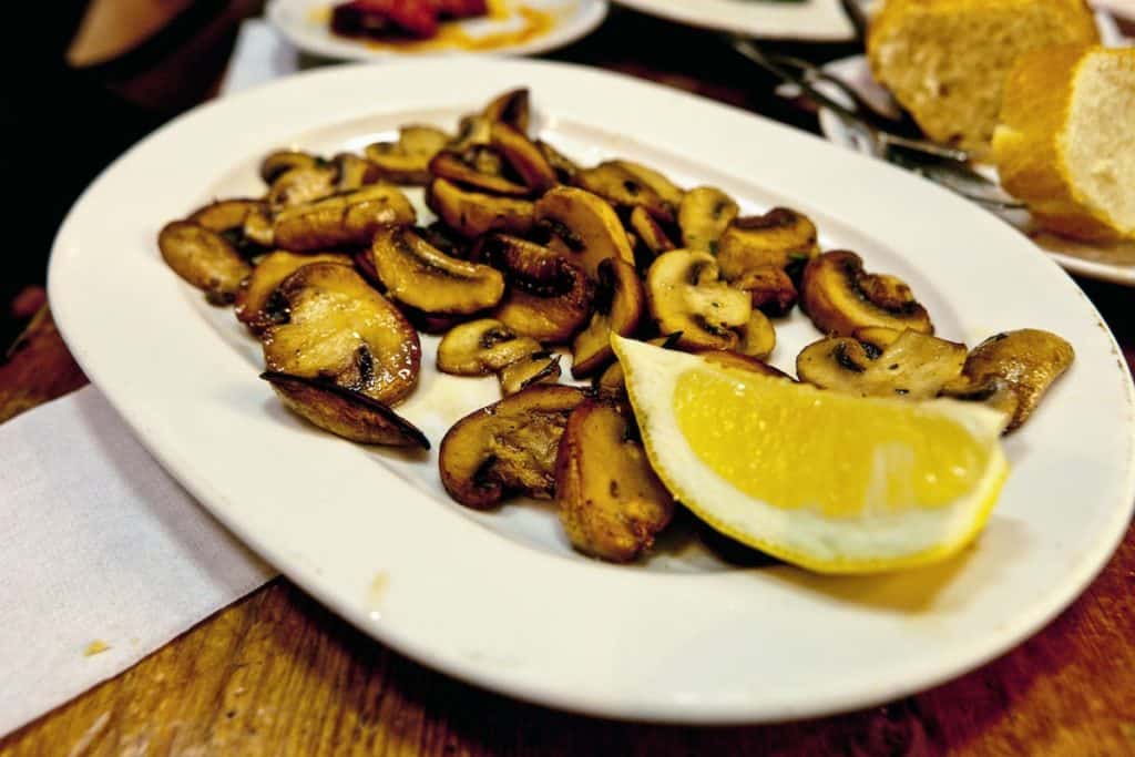 Plate of grilled mushrooms with a lemon wedge.