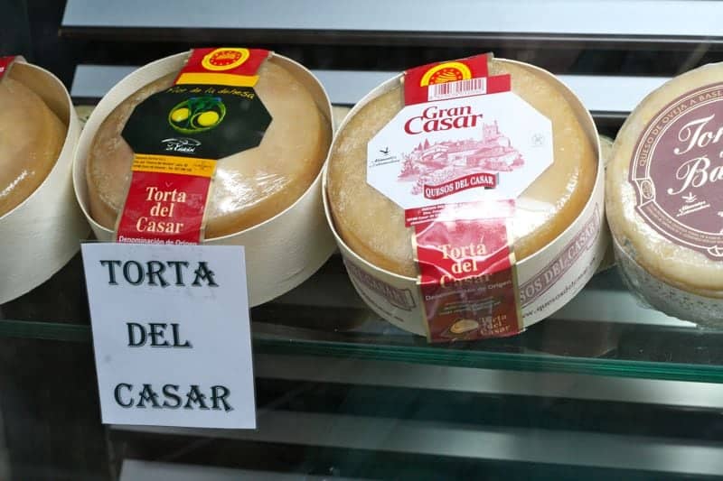 A row of packaged cheese wheels with labels that read "Torta del Casar."