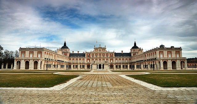 Wide view of the Aranjuez Royal Palace, with a large lawn and wide path in front.