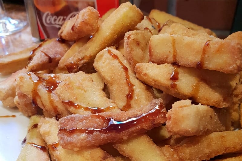 Close-up of a pile of fried eggplant pieces drizzled with brown molasses.