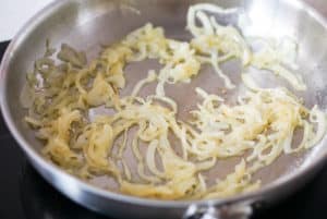 Sliced onions caramelizing in a frying pan for tortilla de patatas
