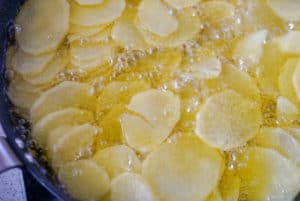 Sliced potatoes frying in olive oil to make Spanish tortilla