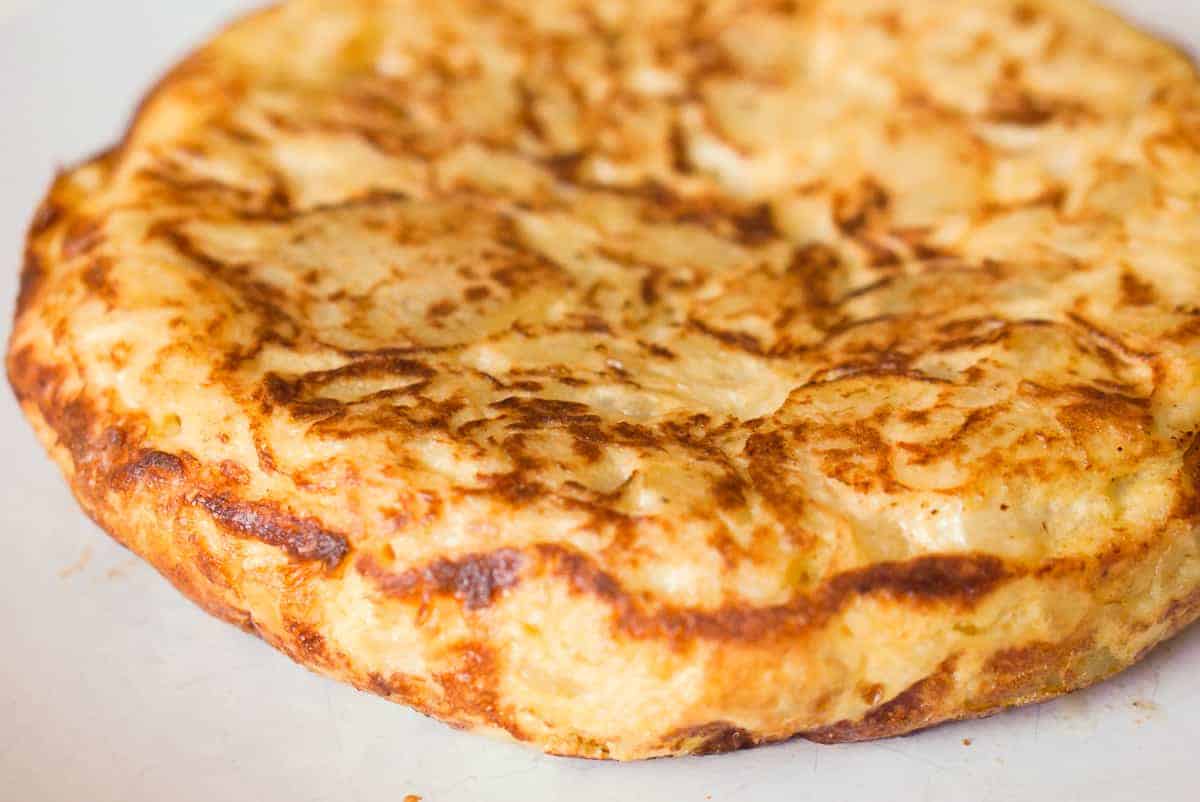 Finished Spanish omelet, the tortilla de patatas on a white plate.