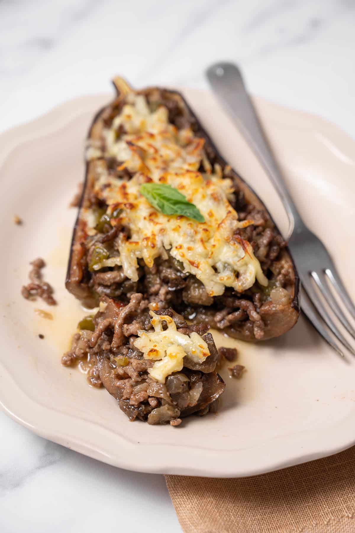 A plate with a stuffed eggplant with a bite taken out of it.