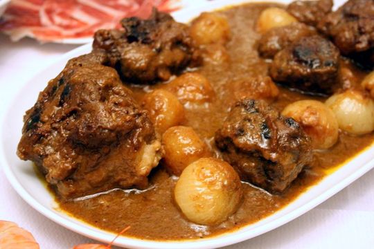 A large platter of braised bull tail stew with potatoes, onions, and lots of sauce.