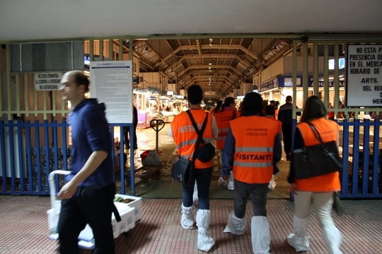 A group of people in orange vests walking into the Mercamadrid market.