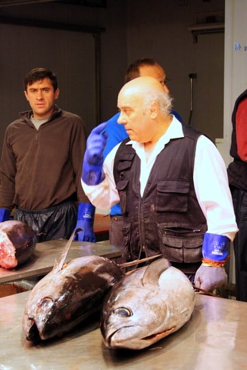 A gloved worker at Mercamadrid stands in front of two huge raw fish.