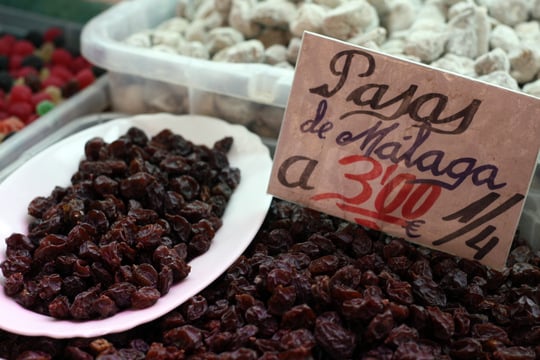 Raisins in a bulk bin at a Malaga market, with a sign to label them.