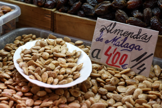 Almonds in a bulk bin at a Malaga market, with a sign to label them.