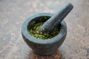 Mixing garlic, parsley, salt and pepper in a mortar and pestle.