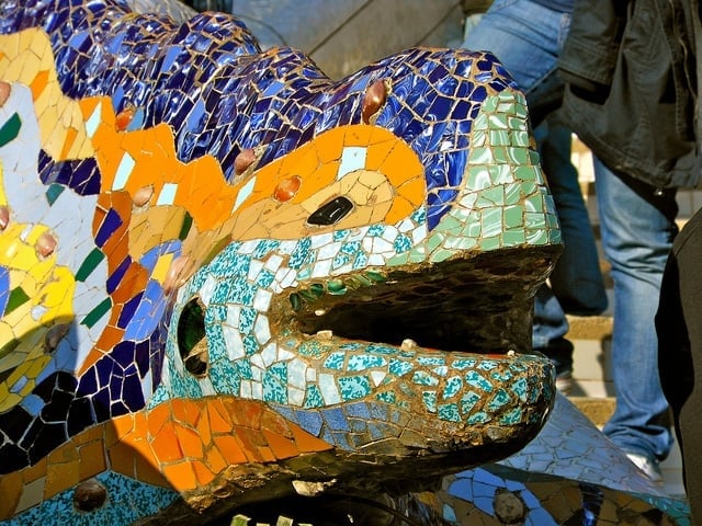 Close-up of a large statue of a reptile covered in colorful mosaic tiles at Park Güell.