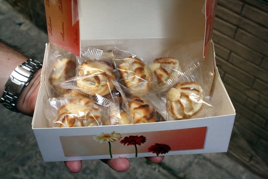 Someone holding a paper box of individually wrapped marzipan sweets.