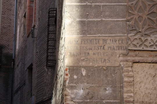 Close-up of an ancient sign on the wall of a square, with painted writing in Spanish.