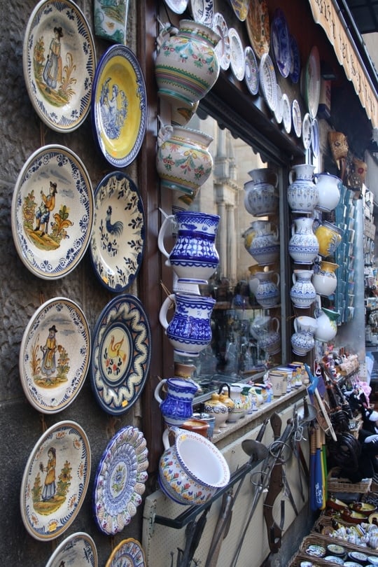 The outside of a souvenir shop in Segovia, with painted ceramics hanging from its walls.