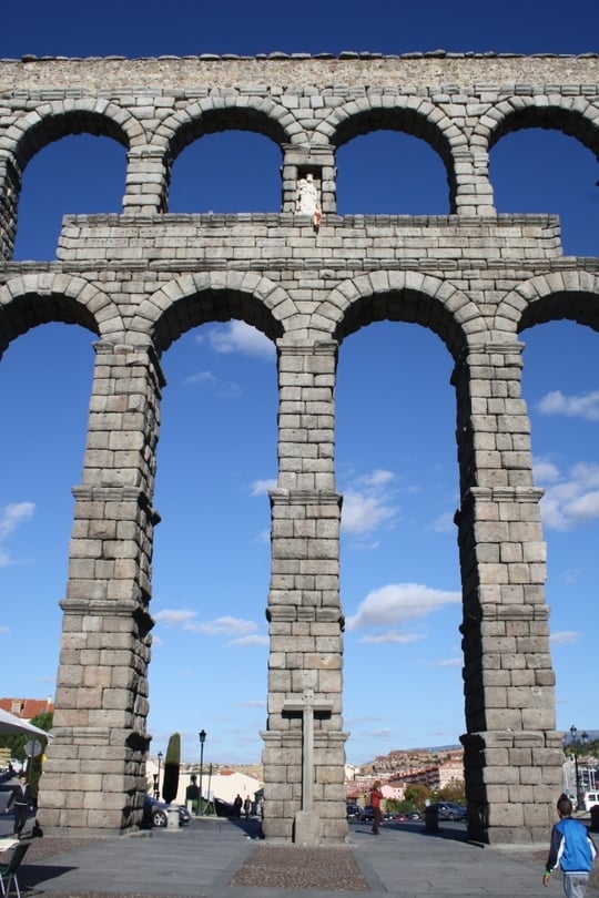 A stone aqueduct with two levels of tall columns and arches, and blue sky behind it.