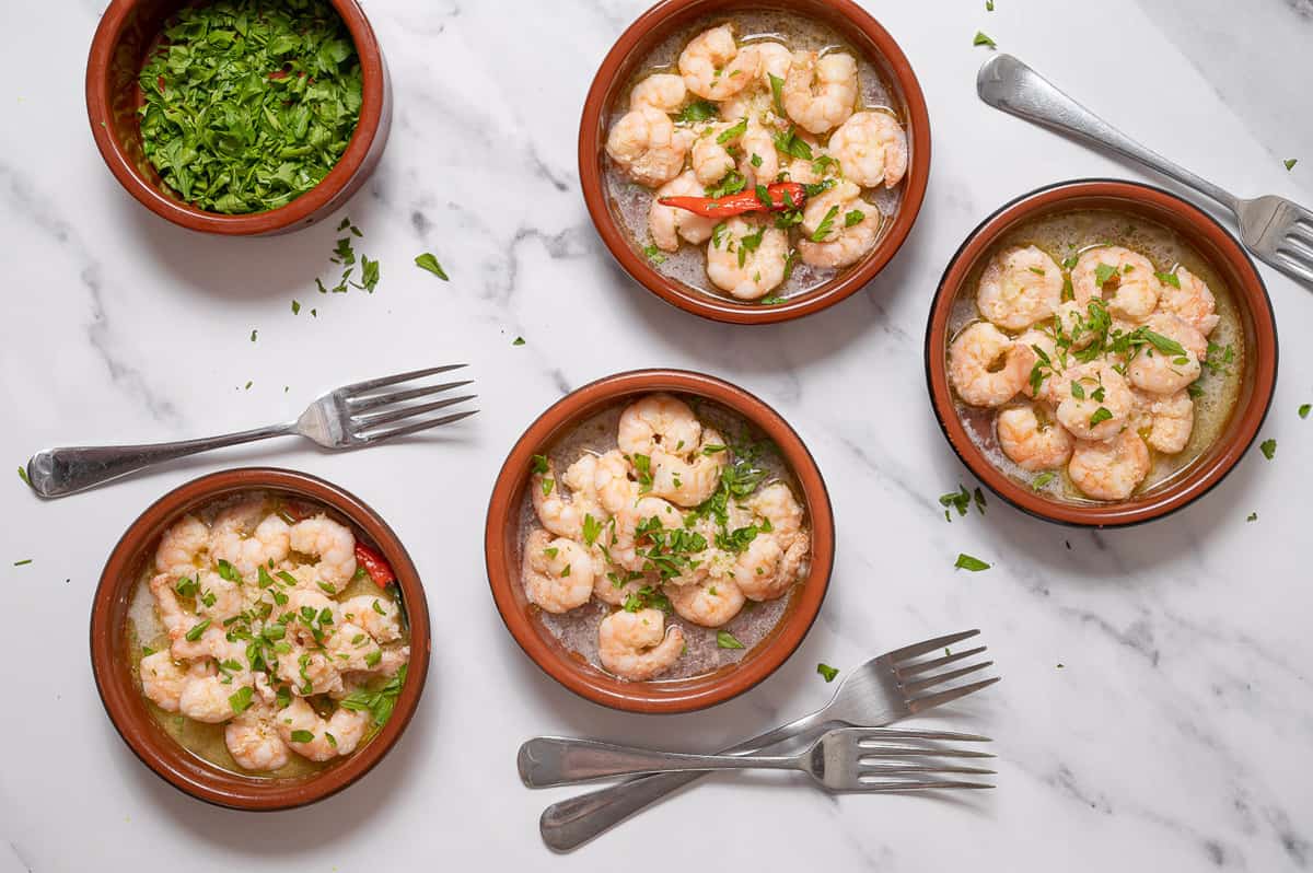 Gambas al ajillo tapa of garlic shrimp in clay dishes topped with chopped parsley