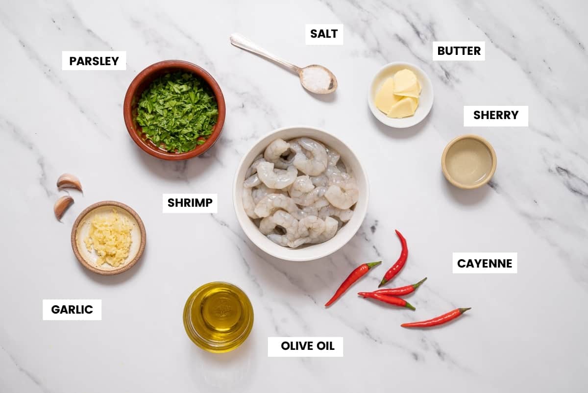 Ingredients to make Spanish garlic shrimp on a white marble countertop.