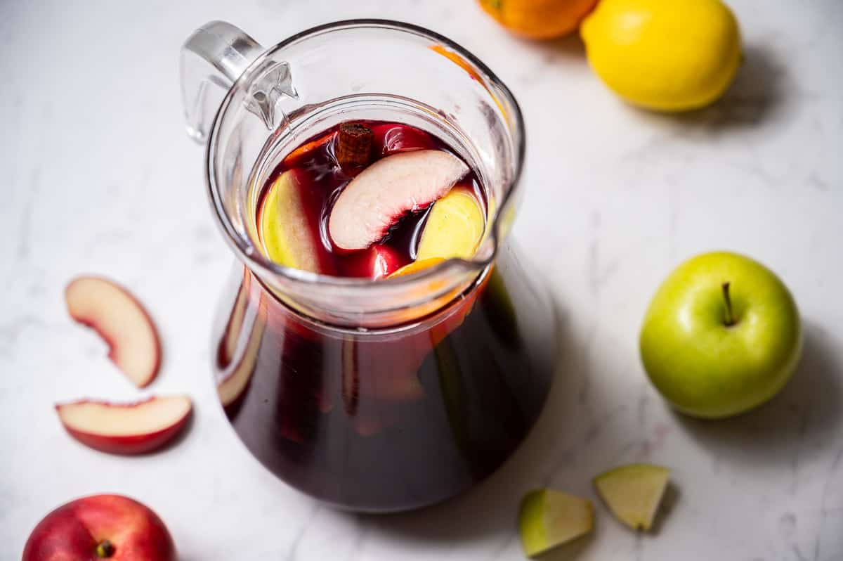 Pitcher of red wine sangria with apple, nectarine, lemon, and orange.