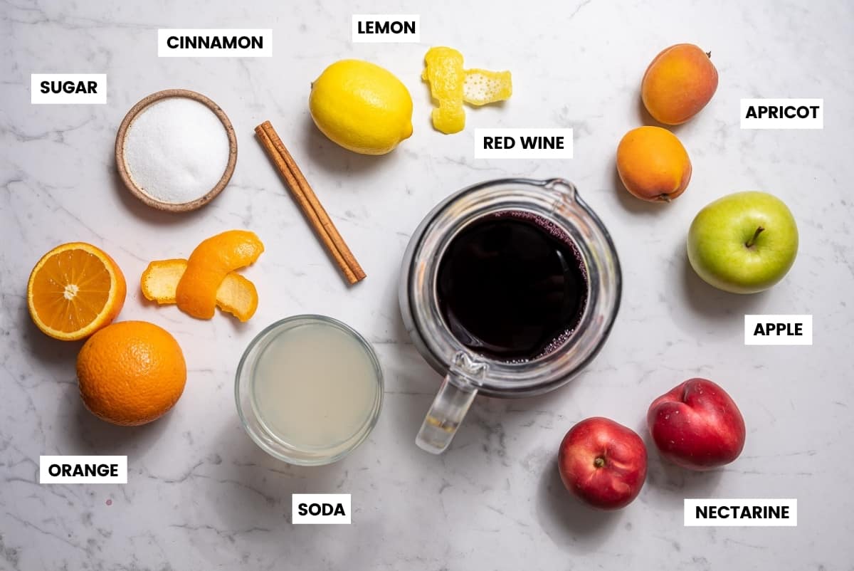 Ingredients for Spanish sangria laid out on a white countertop.