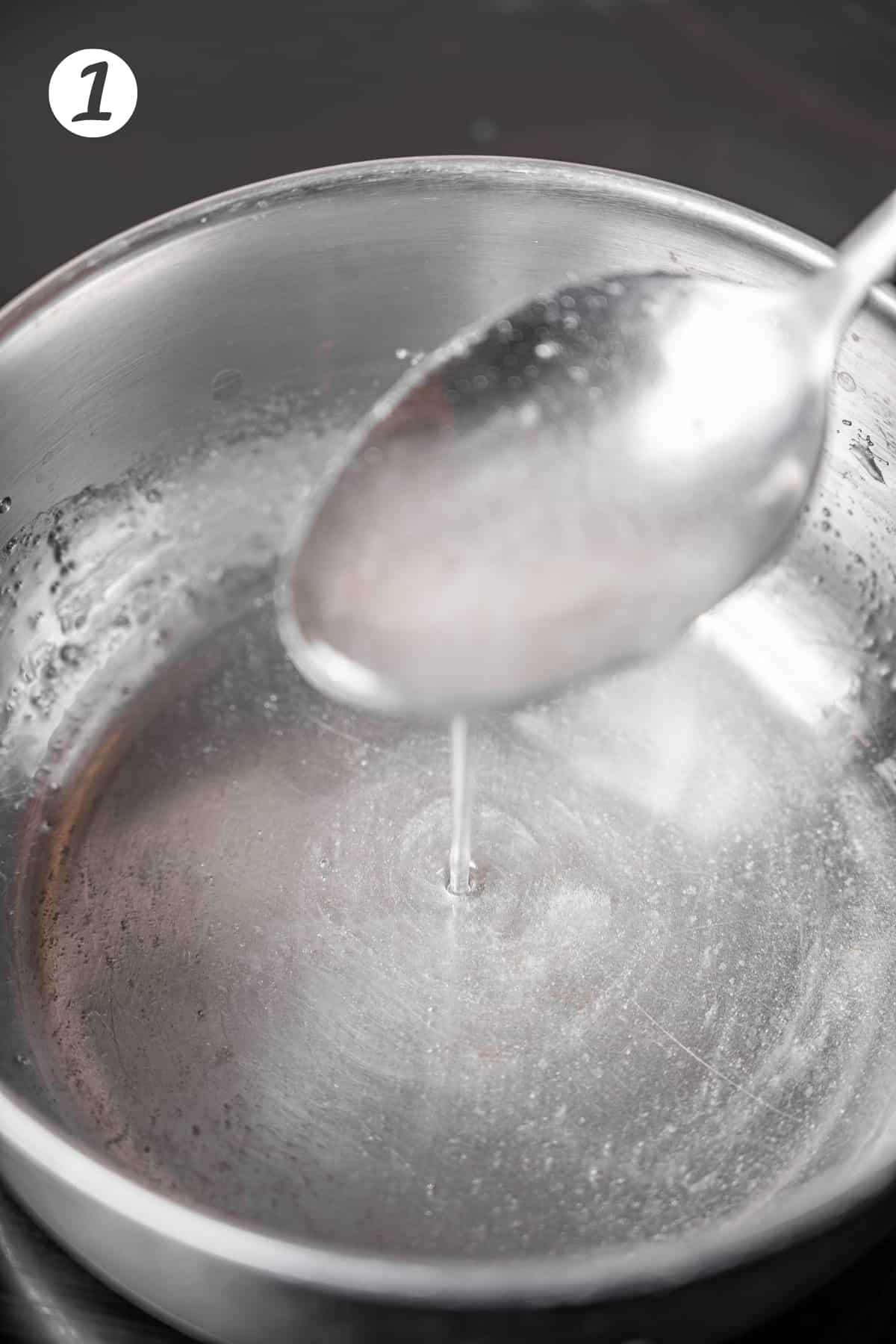 Metal pot filled with simple syrup and a metal spoon.