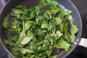 Fresh spinach wilting in a frying pan