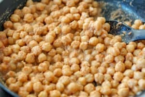 Coating the chickpeas with almond paste in a large pan