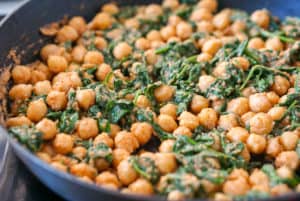 Spinach and chickpea stew in a frying pan on the stovetop.