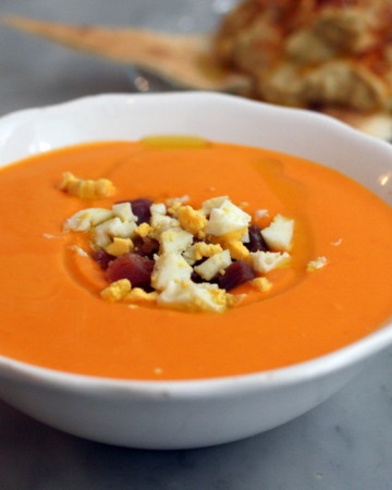 best salmorejo recipe in a white bowl topped with hard boiled egg and ham