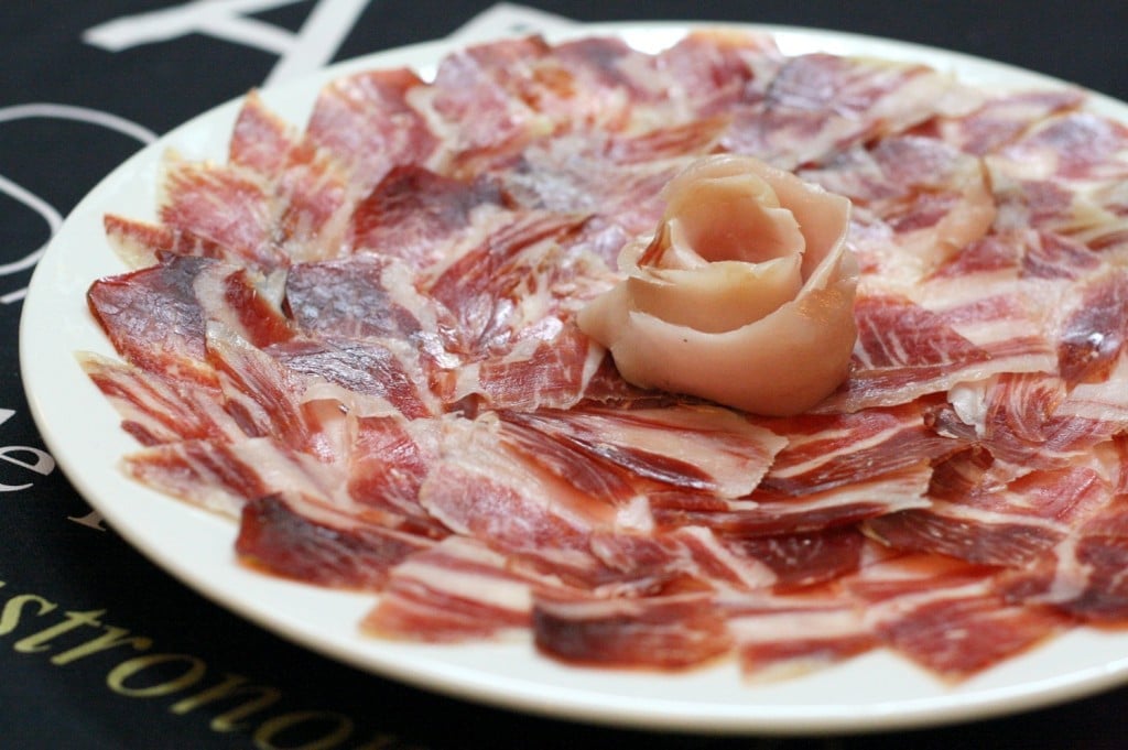 A plate of thinly sliced pieces of Iberian cured ham, arranged in a circle.