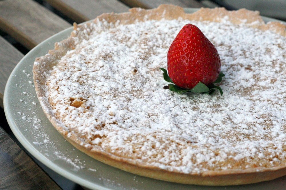 Tarta de Santiago, or Spanish almond cake, dusted with powdered sugar and topped with a strawberry.