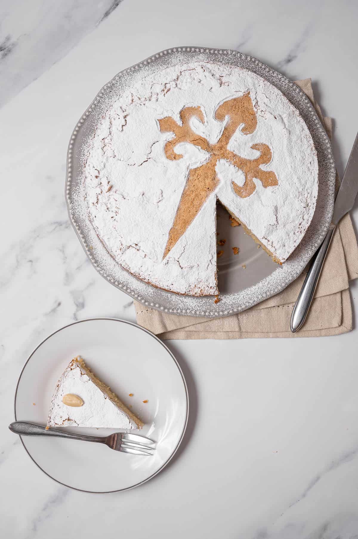 Tarta de Santiago with a cross of Saint James design on a white plate.