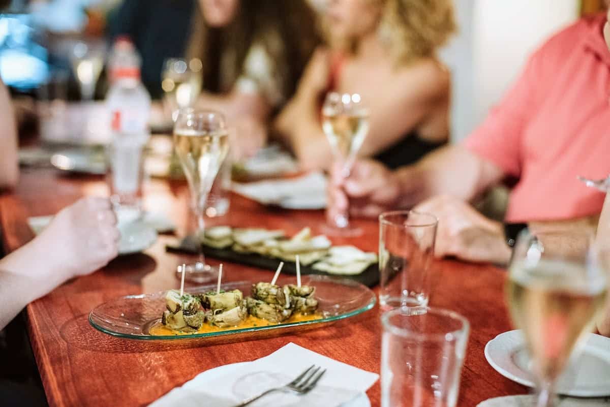 Artichoke and romesco sauce tapas on a table with several glasses of sparkling wine.