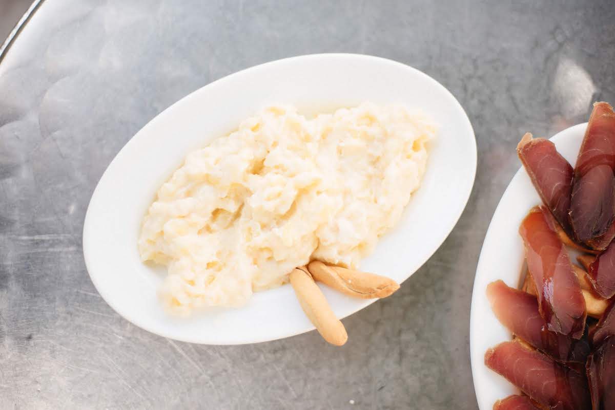 Overhead shot of Russian salad with breadstick crackers on a metal surface