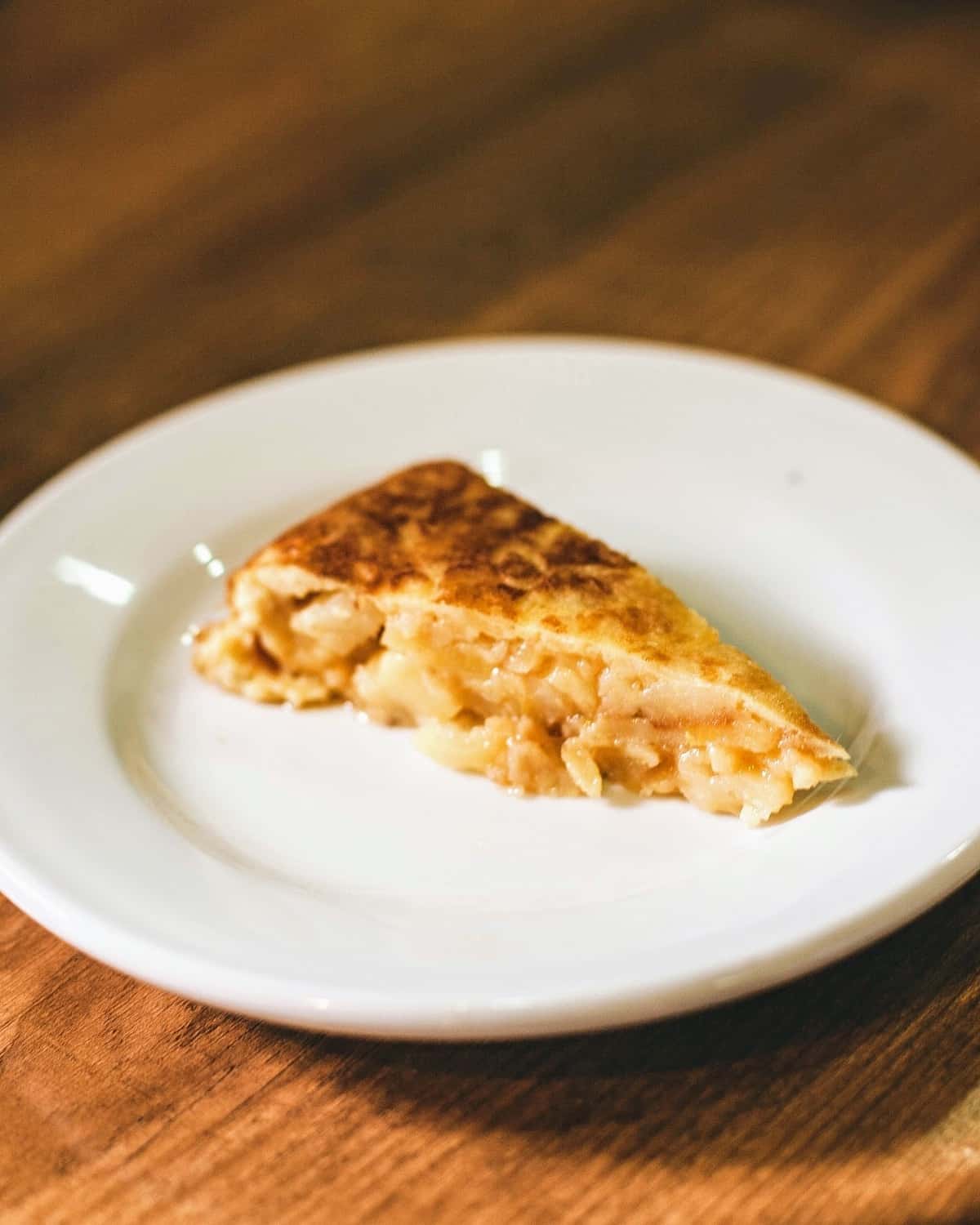 Slice of Spanish potato omelet on a white plate