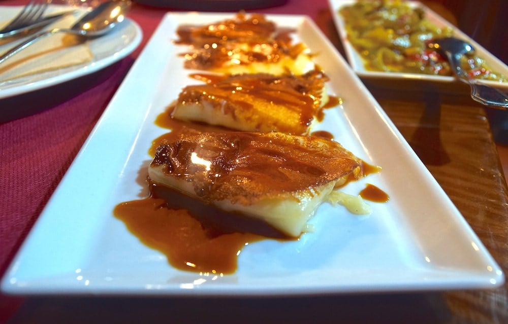 Close-up of a plate of triangular cheese slices covered in golden-brown palm honey.