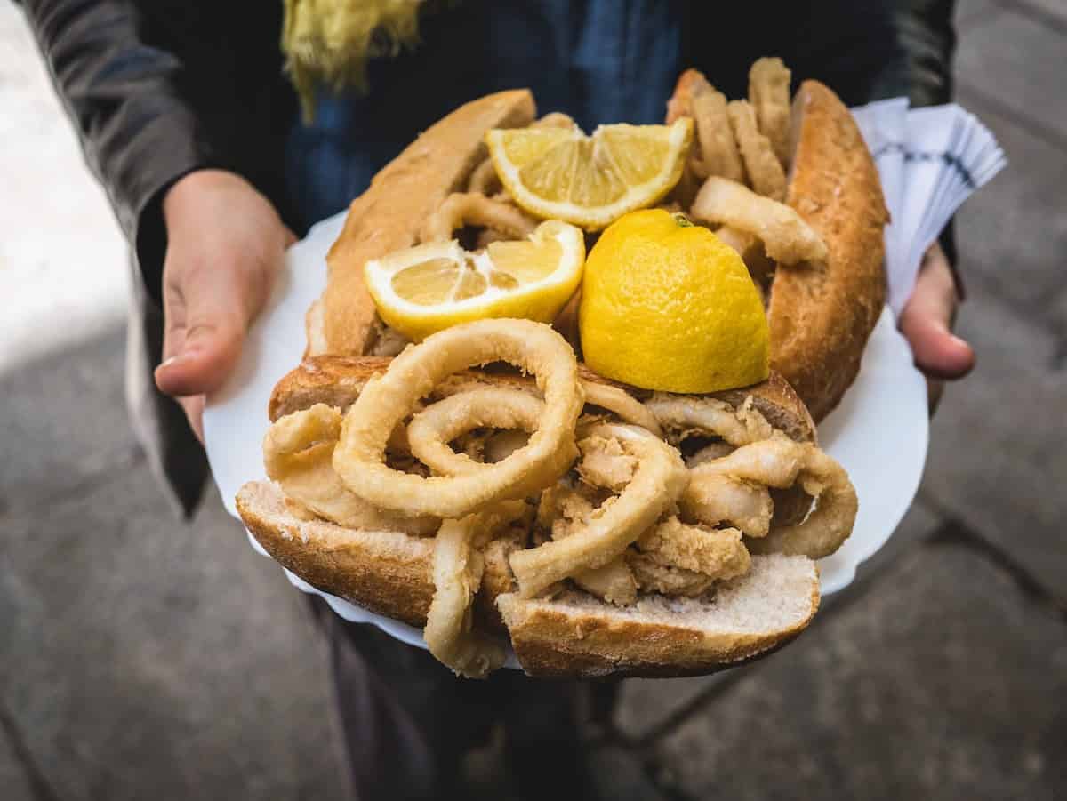 Fried calamari sandwiches with lemon slices on a white plate