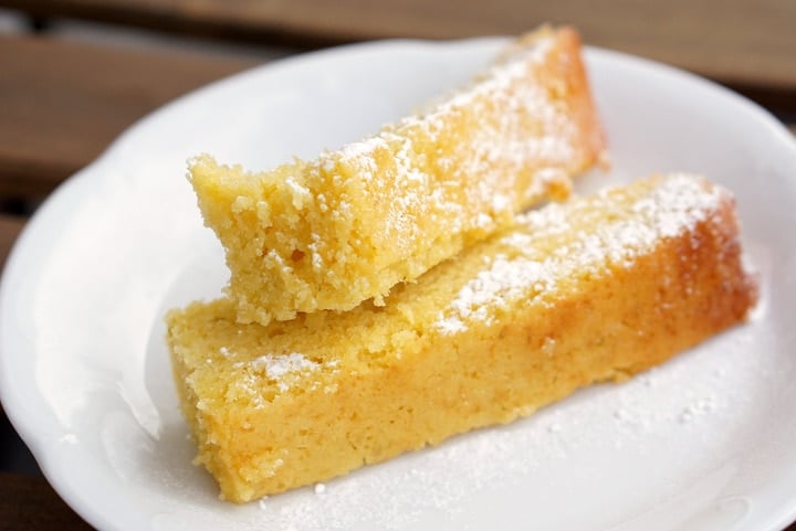 Two rectangular slices of moist lemon olive oil cake dusted with powdered sugar.