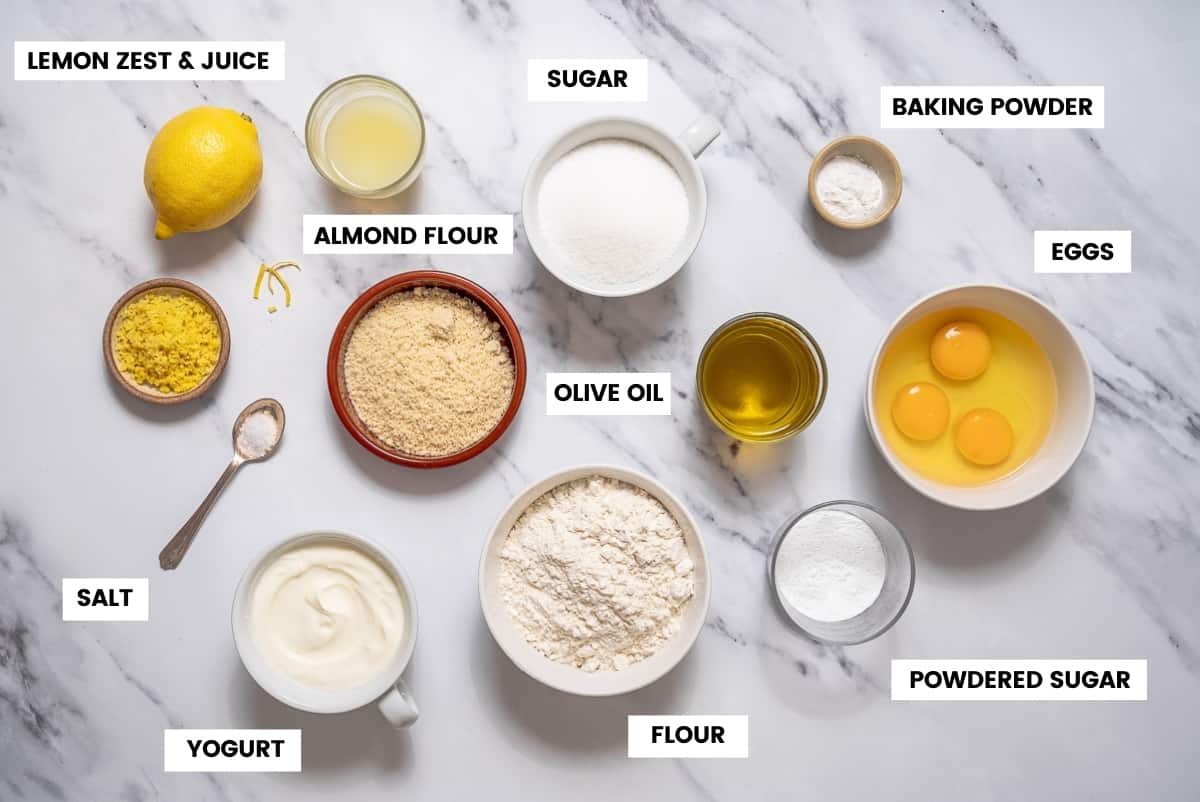 Lemon olive oil cake ingredients on a white marble countertop