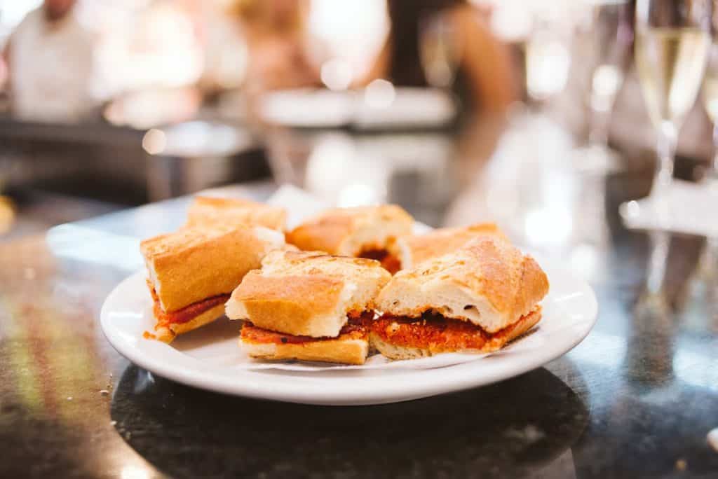 Small sandwiches filled with red sausage on a white plate