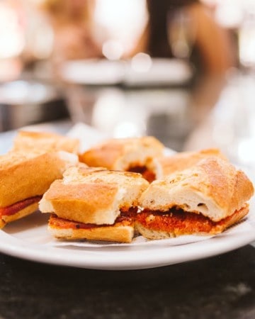 Small sandwiches filled with red sausage on a white plate