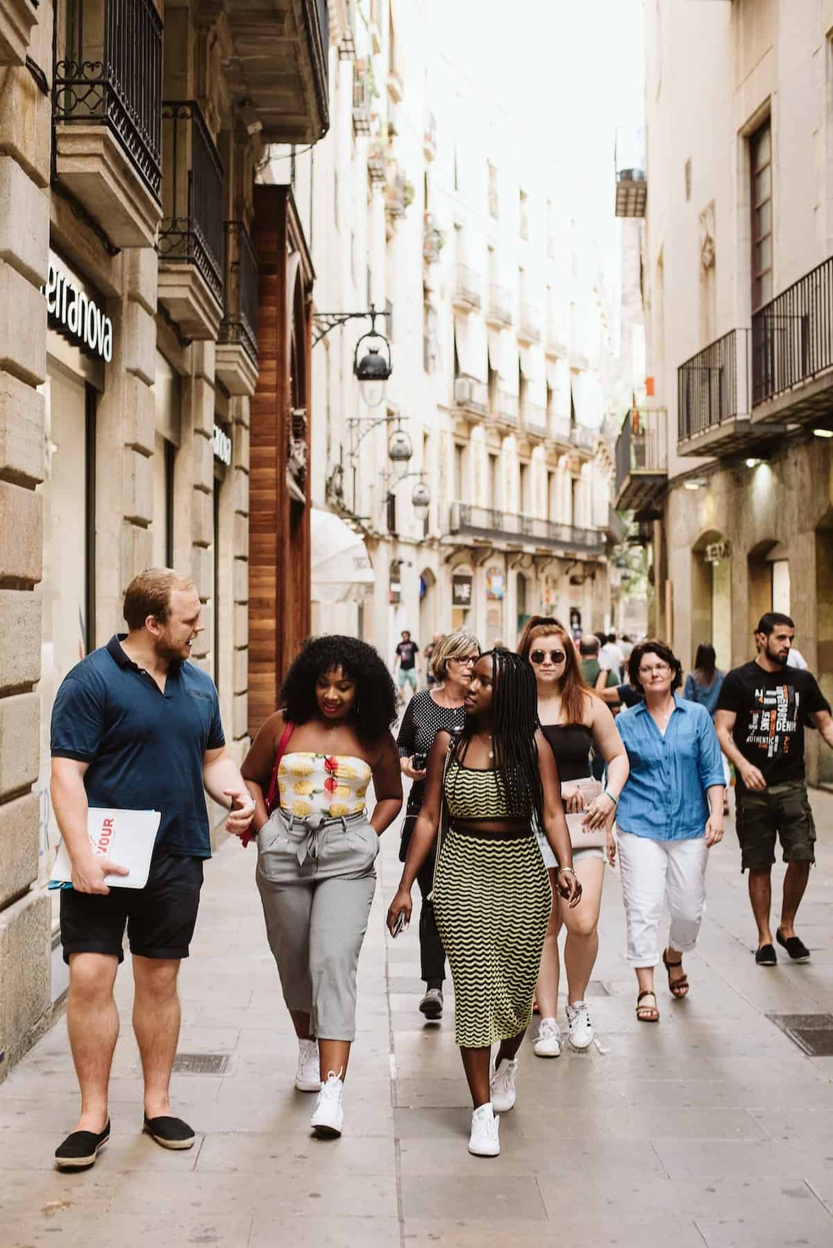 A group of young people walking down the street in a Spanish city.