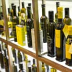 Many bottles of olive oil on a store shelf.
