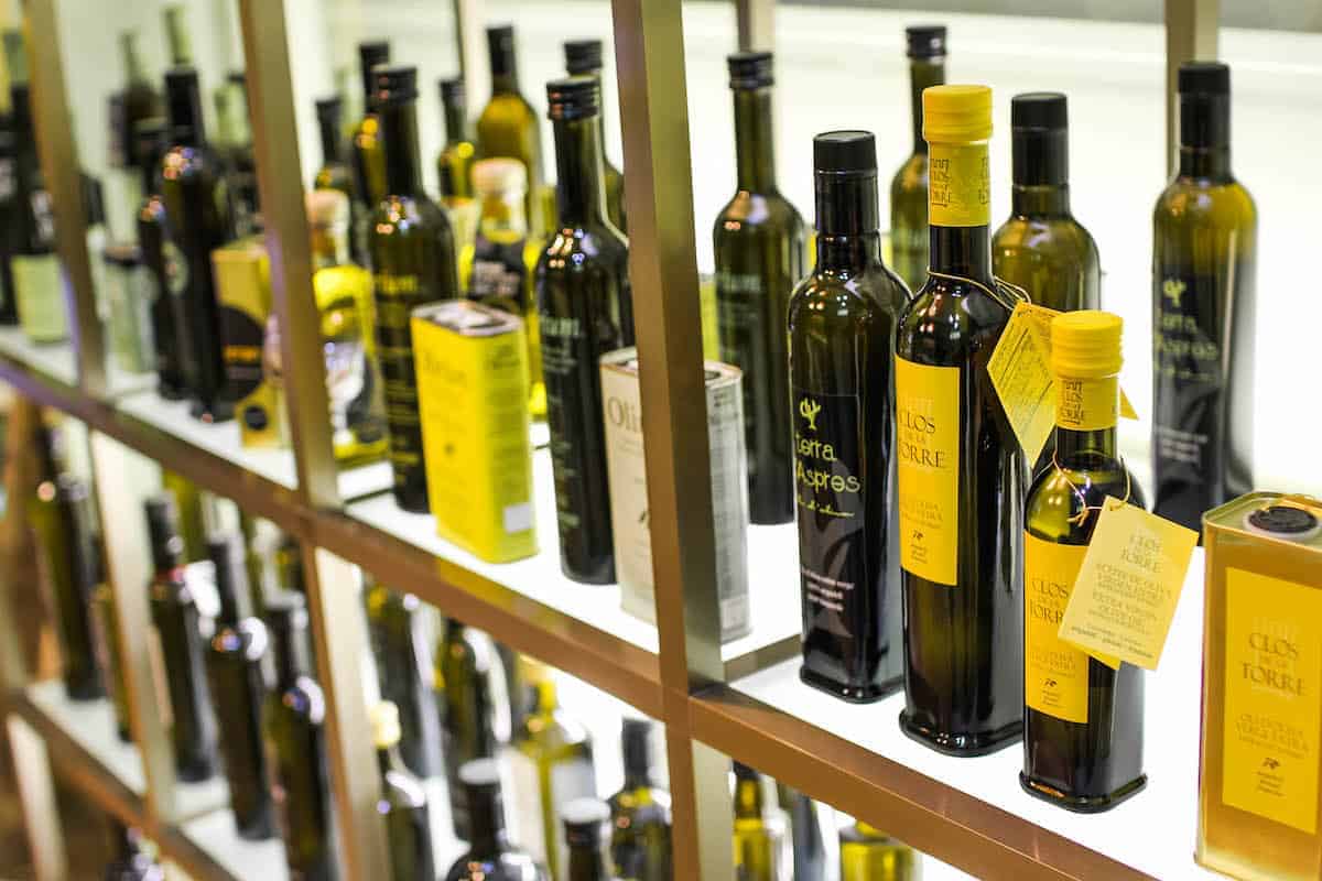 Many bottles of olive oil on a store shelf.