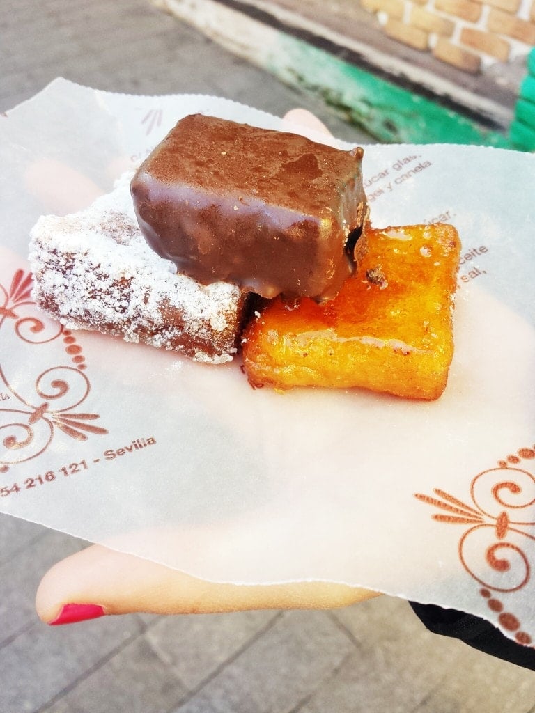 Three different types of torrijas covered in chocolate, powdered sugar, and sweet syrup.