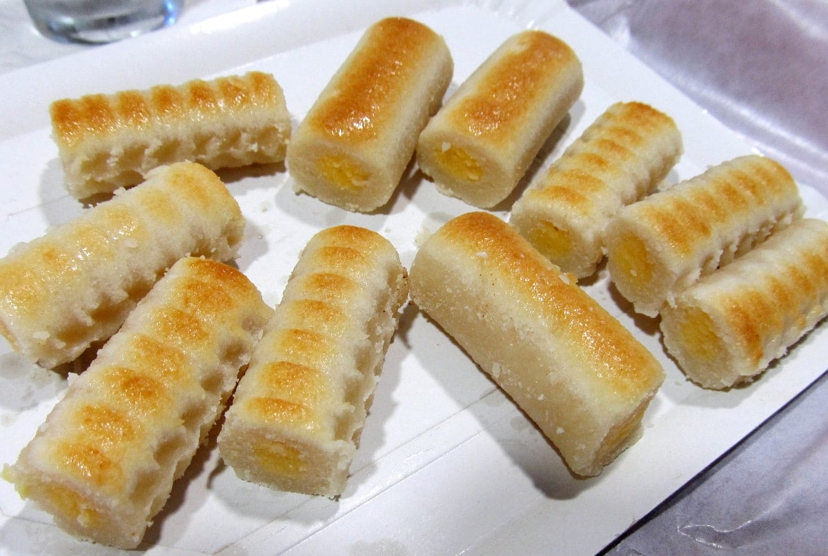 A tray of small marzipan cylinders with egg yolk filling and golden-brown ridges on top.