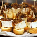 Small pieces of crusty bread topped with goat cheese and caramelized onions, all held together with a toothpick.